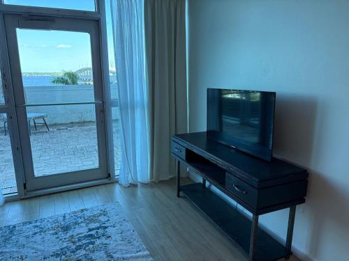 a television sitting on a dresser in a living room with a window at Aqua Breeze Paradise in Fort Myers