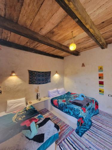 two beds in a room with wooden ceilings at Gazrashek Siwa Hot spring& trips Haven in Siwa