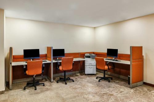 an office with three desks with computers and orange chairs at Fiesta Inn Express Puebla Finsa in Puebla