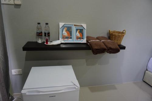 a bathroom with a shelf with bottles and towels at Meephawa Resort in Amphawa