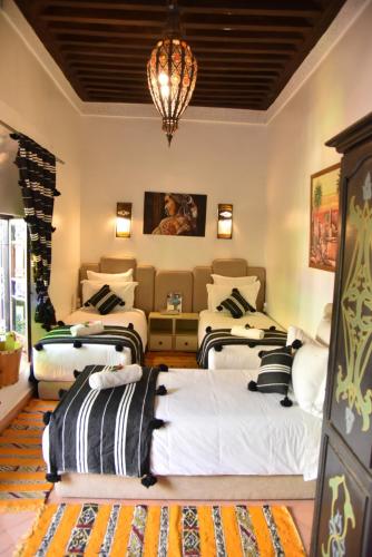 a room with four beds and a chandelier at Riad Du Petit Prince in Marrakesh
