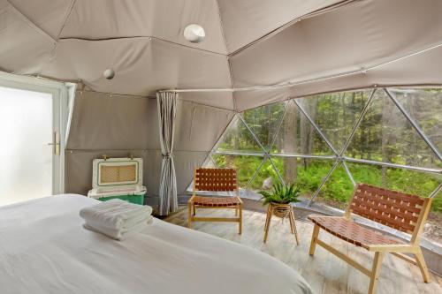 a bedroom with a bed and two chairs and a tv at Ferncrest Campground in Greentown