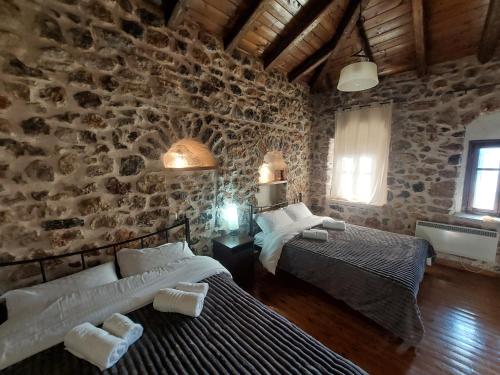 a bedroom with two beds and a stone wall at Andromahi Stone House in Stemnitsa