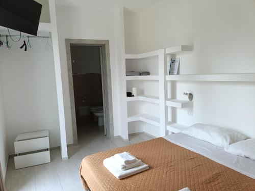 a white bedroom with a bed with towels on it at SeA Beach Home in Torre Lapillo