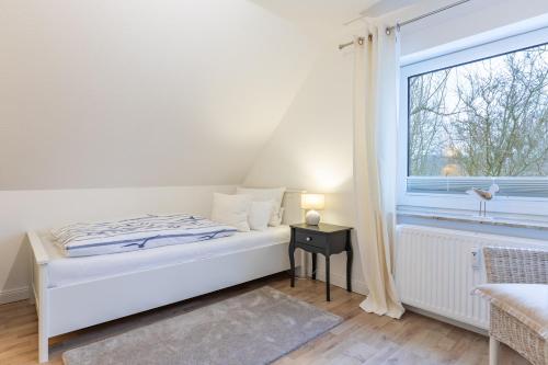 a white bedroom with a bed and a window at Hjertets Hus in Humptrup