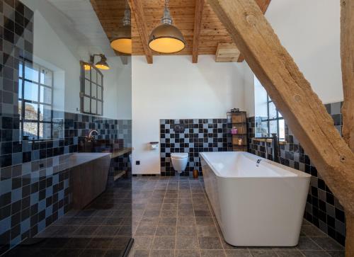 a bathroom with a large tub and black and white tiles at Scheune 1746 in Tating