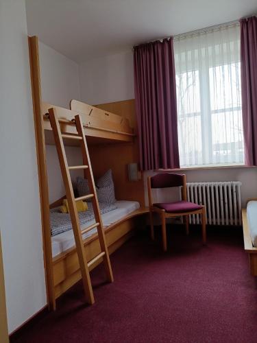 a bedroom with two bunk beds and a chair at Haus Lutherrose in Neuendettelsau