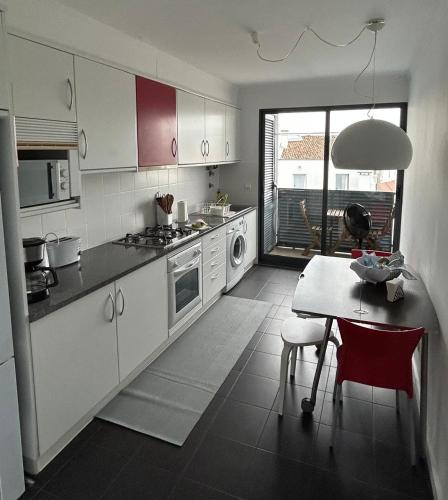 a kitchen with white cabinets and a table with red chairs at 2Stay - A1 in Ponta Delgada