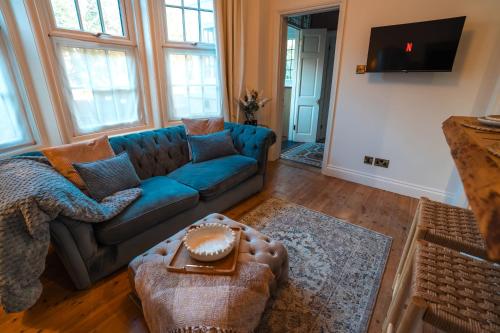 a living room with a blue couch and some windows at Period apartment in the heart of Bournemouth in Bournemouth