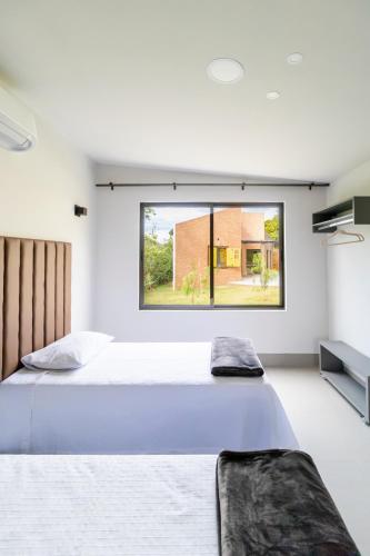 two beds in a bedroom with a large window at TABULEIRO loft novo, moderno e espaçoso in Ouro Preto
