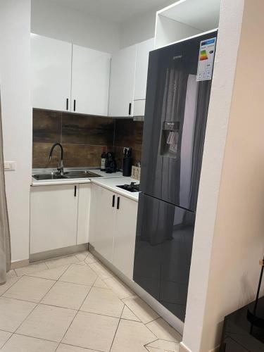 a kitchen with white cabinets and a black refrigerator at Larriba Santa Maria by RPG Group in Santa Maria