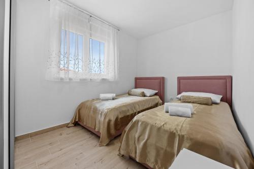 two beds in a white room with a window at Apartment Lola in Peroj