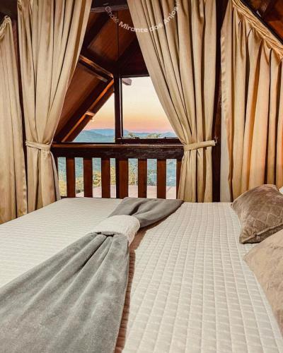 a bed in a room with curtains on it at Chalé Mirante dos Anjos in Rodeio