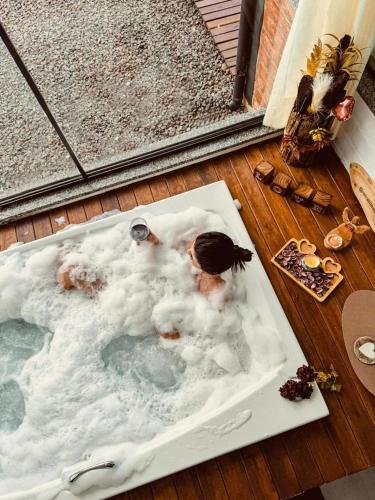 two people in a jacuzzi tub on a deck at Chalé Mirante dos Anjos in Rodeio