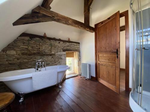 a bathroom with a large tub and a stone wall at Chez le Cavalier in Génis