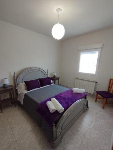 a bedroom with a large bed with purple sheets and pillows at Alojamiento La Tortuga in Las Navas del Marqués