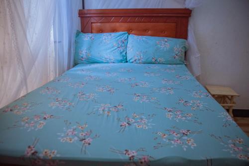 un letto con un copriletto blu con dei fiori sopra di Makinihomestay ad Arusha