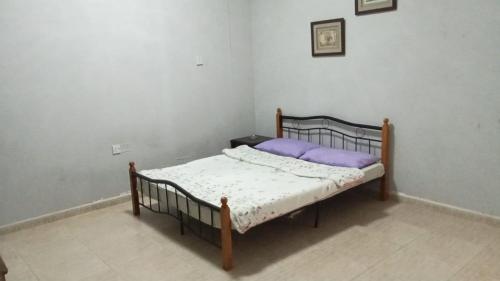 a small bedroom with a bed with a purple pillow at House Al Ain - 5 in Al Ain