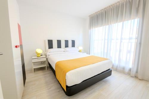 a white bedroom with a large bed and a window at Castell Beach Aparthotel in Castelldefels