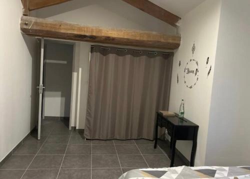 a bedroom with a bed and a curtain and a table at Chez aurelie in Agnin