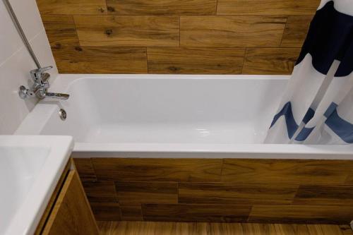 a bathroom with a white bath tub with a wooden floor at Center 2 poverh Ecoflow VIP TopApart in Sumy