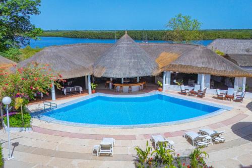 a resort with a swimming pool and tables and chairs at Keur Saloum Resort in Toubakouta