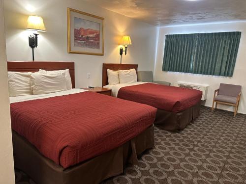a hotel room with two beds and a chair at Canyonlands Motor Inn in Monticello