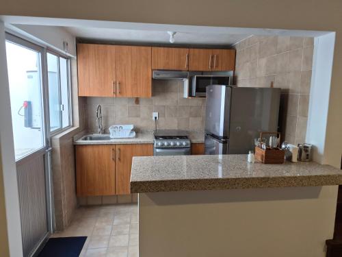 a kitchen with wooden cabinets and a stainless steel refrigerator at Casa del Árbol Querétaro in Querétaro