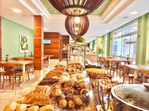 a bakery with a bunch of pastries on a table at CAPÃO Da CANOA MAR HOTEL in Capão da Canoa