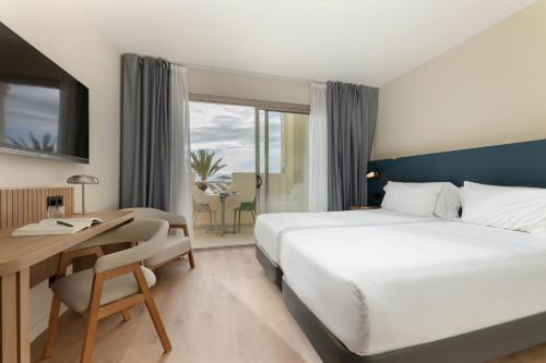 a hotel room with a large bed and a desk and a desk at Sercotel Kalma Sitges in Sitges