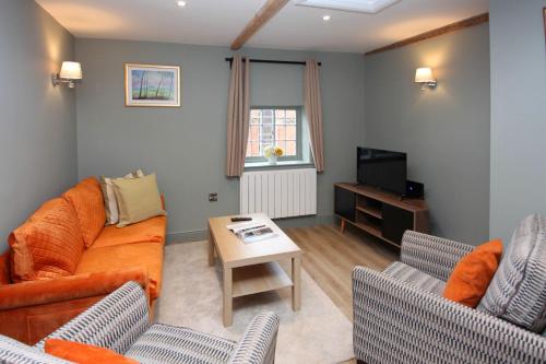 a living room with a couch and a tv at St John's Hill Apartments in Shrewsbury