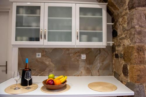 a kitchen counter with a bowl of fruit and a bottle of wine at Kos View City , Luxury Old Town in Kos