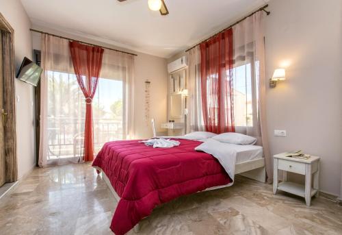 a bedroom with a red bed and a large window at Agali Villa in Limenaria