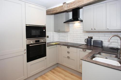a white kitchen with white cabinets and a sink at St John's Hill Apartments in Shrewsbury