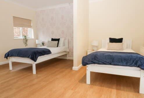a bedroom with two white beds and a wooden floor at Walworth Castle Cottage in Darlington