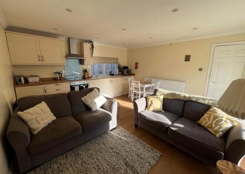 a living room with two couches and a kitchen at Walworth Castle Cottage in Darlington