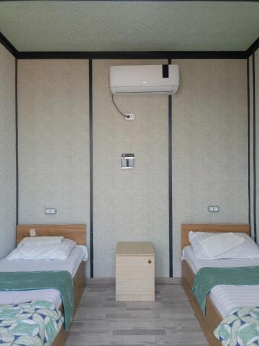 a room with two beds and a air conditioner at Aydarkul Beach in Taldy