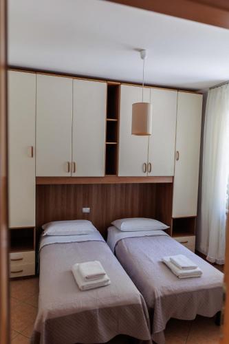 two beds in a room with white cabinets at Casa Giordana in Torri del Benaco