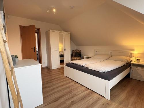 a bedroom with a white bed and wooden floors at Hallighafen in Bredstedt