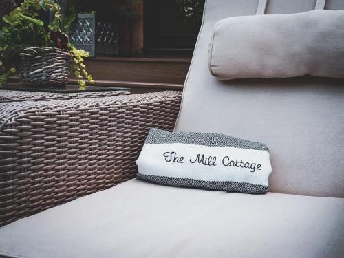 a white couch with a pillow that says the uk cottage at Pool House at Mill Cottage in Goring