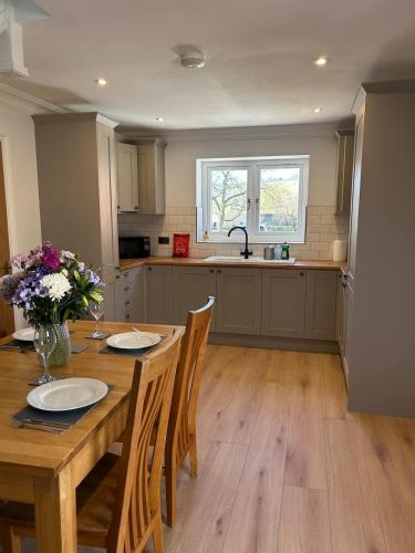 a kitchen with a wooden table with chairs and flowers at Goring River Retreat with Gym and Wellness Area in Goring