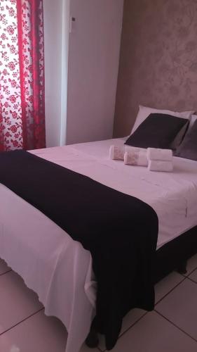 a bed with black and white sheets and pillows at Apartamento Inteiro Foz do Iguaçu Prox Rodoviaria in Foz do Iguaçu