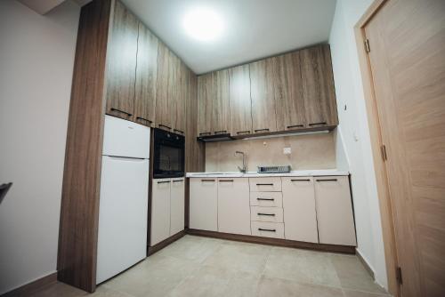 a kitchen with wooden cabinets and a white refrigerator at NeWave Apartment 2 in Strumica