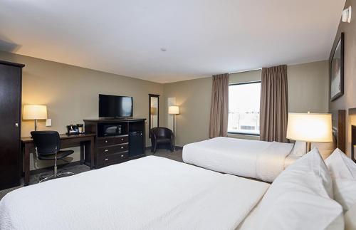 a hotel room with two beds and a desk and a television at Canad Inns Destination Centre Transcona in Winnipeg