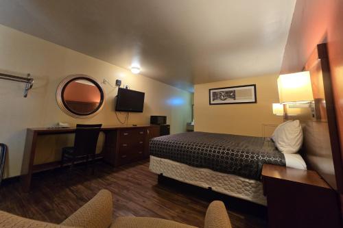 a hotel room with a bed and a desk and a mirror at Sunrise Inn By OYO Newport News US-60 in Stoney Brook Estates