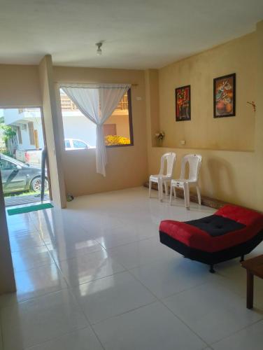 a living room with two white chairs and a red ottoman at PAULIN Surf in Montañita