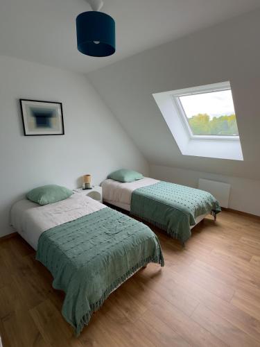 two beds in a white room with a window at La maison des étangs in Rebecques