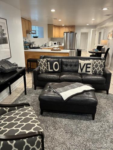 a living room with a black leather couch and a kitchen at The Wrigleyville Garden 200 Steps to Wrigley-2BR in Chicago