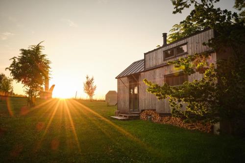 a barn in a field with the sun setting at Arboretum Vlasenice in Vlasenice