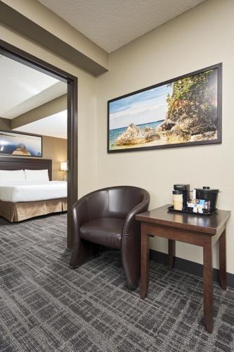 a hotel room with a bed and a chair and a table at Canad Inns Destination Centre Transcona in Winnipeg